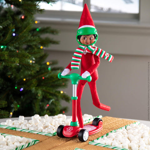 elf on the shelf op een scooter step met helm en gestreepte sjaal